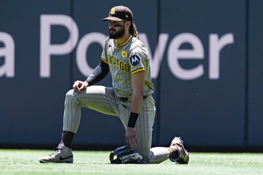 Fernando Tatis Jr. watching from one knee during a break in the game