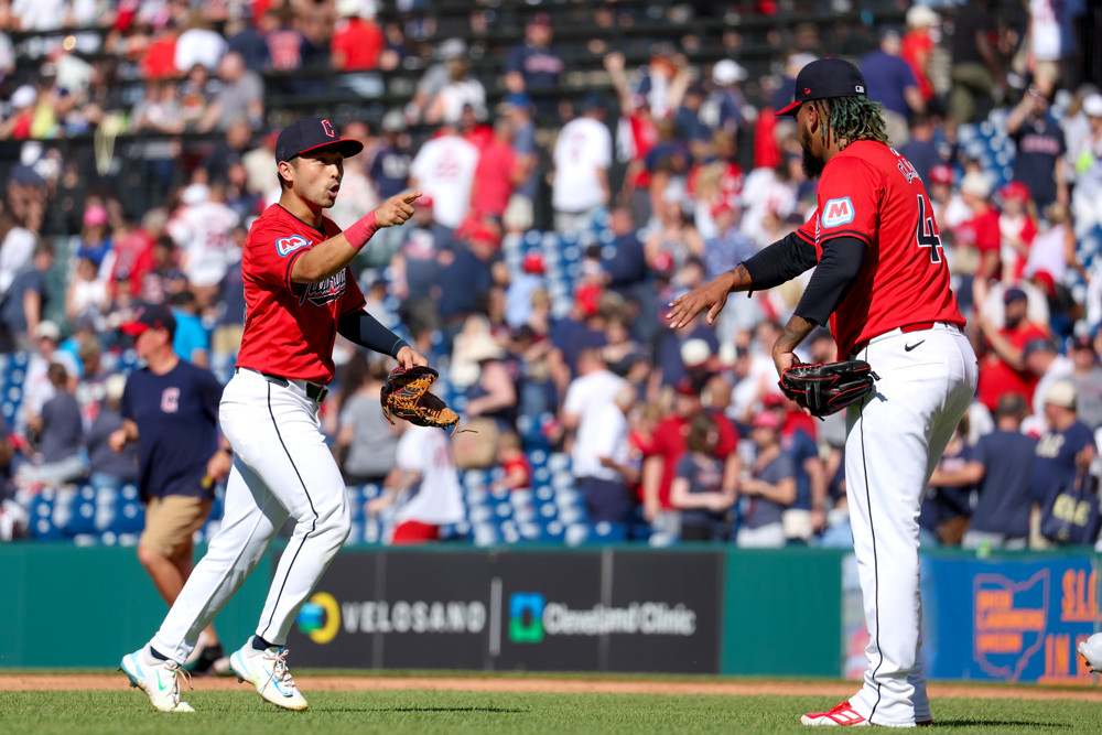 Emmanuel Clase, in a red jersey with white pants, waits to give a high-5 to teammate Steven Kwan after the Guardians defeated the Blue Jays.